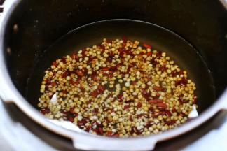 接着放入电压力锅，加入适量的水，按“煮粥”键开始煮红豆薏米汤。

