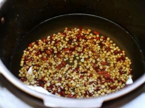 接着放入电压力锅，加入适量的水，按“煮粥”键开始煮红豆薏米汤。

