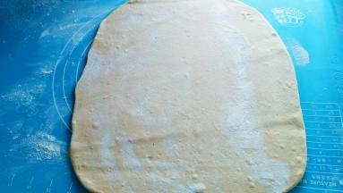 在把面团擀成较薄一点的大片。