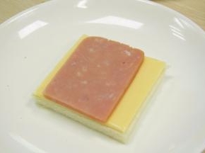 这时开始合拼啰，取出一块吐司片，放上奶酪片和午餐肉。