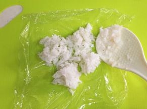 在150克的米饭中加入少许寿司醋拌匀，然后取一份50克米饭放在保鲜膜上。