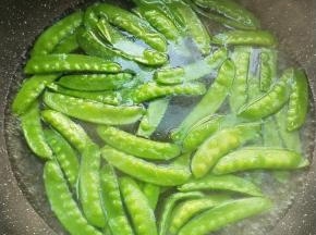 锅中水烧开，加少许盐少许食用油，倒入荷兰豆焯烫一会，捞出放凉水中浸泡，炒前捞出沥干。