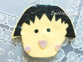 火腿片剪出小丸子的嘴巴和红扑扑的脸蛋，海苔片剪两个眼睛，贴在脸上，然后整个铺到面包上