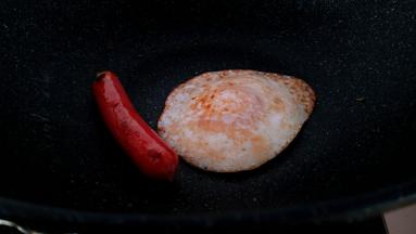在把鸡蛋和热狗肠煎熟。