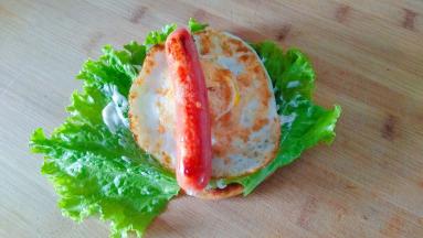 饼上面铺上生菜，涂上沙拉酱，放上鸡蛋和热狗肠。