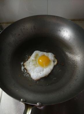 另起锅，锅里加入食用油，油热后敲入鸡蛋（我这里鸡蛋白煎熟，蛋黄还处于可流动状态，喜欢全熟鸡蛋的朋友可以慢火将鸡蛋煎熟），加入少量的盐调味；