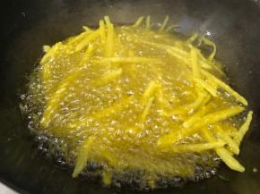 慢慢的撒入拌好淀粉的土豆丝，中火炸至定型后，开大火，用筷子轻轻将土豆丝摆散开