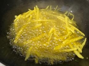 慢慢的撒入拌好淀粉的土豆丝，中火炸至定型后，开大火，用筷子轻轻将土豆丝摆散开