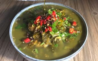 将热油淋在鱼杂酸菜汤的花椒上