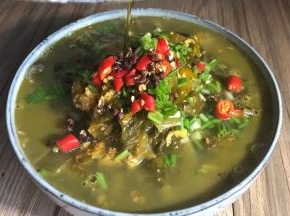 将热油淋在鱼杂酸菜汤的花椒上