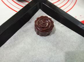 把月饼生坯扣出来，，放入垫了油纸的烤盘中。