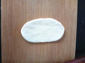 取一份面团，光面向上，拍几下排气，然后擀成椭圆形。