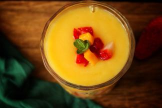 切一些草莓贴在杯子上，倒入做好的冰沙，表面在装饰水果和薄荷叶子，漂亮有颜值的雪梨芒果冰沙就做好了