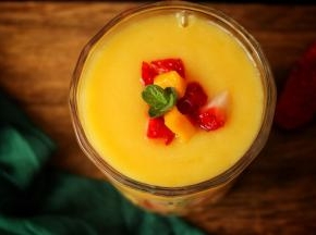 切一些草莓贴在杯子上，倒入做好的冰沙，表面在装饰水果和薄荷叶子，漂亮有颜值的雪梨芒果冰沙就做好了