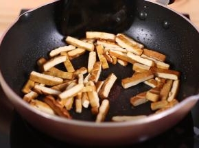 锅中再次加少许的油，油热后加入香干，大火翻炒2分钟，