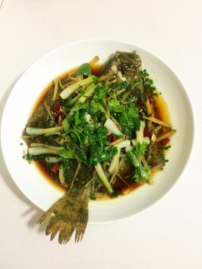 把盘子里蒸出来的水倒掉，放入适量的蒸鱼豉油，葱花，把烧热的香油浇在鱼身上，摆上香菜段即可上桌啦！
