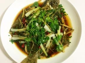 把盘子里蒸出来的水倒掉，放入适量的蒸鱼豉油，葱花，把烧热的香油浇在鱼身上，摆上香菜段即可上桌啦！