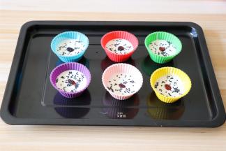 倒入硅胶模具中，表面撒适量熟黑芝麻，中间放上一颗蔓越莓干；