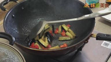 然后加入少量清水（大约1汤勺），再倒入茄子，翻炒均匀