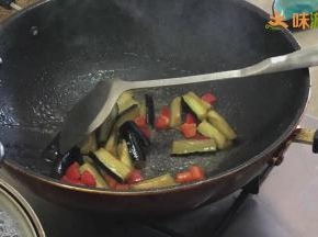 然后加入少量清水（大约1汤勺），再倒入茄子，翻炒均匀
