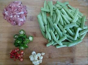 豆角用手摘断，余干椒和小米椒都切小段，肉切小块，蒜切片。