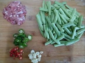 豆角用手摘断，余干椒和小米椒都切小段，肉切小块，蒜切片。