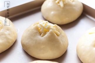 面团发至两倍大后，取出，烤箱210度预热，面团表面薄薄刷一层蛋液，割十字口，在割口里塞进马苏里拉芝士碎