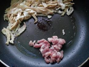 将笋干推至一边，放入瘦肉煸炒