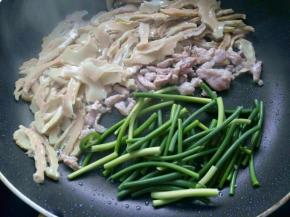 把瘦肉推至一边，下入蒜苗煸炒