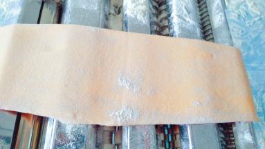 把胡萝卜面团压出合适厚度的面皮。