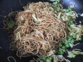 打开锅盖儿后放入豌豆，用筷子将食材炒匀。