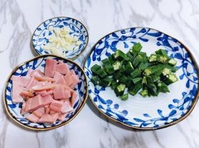 秋葵根切掉，之后再将去跟的秋葵焯水，锅中水烧沸后再加入秋葵，大火煮1分钟立即捞出过冷水，之后淋干水分，再切小段。培根也切小块儿，蒜去皮切碎。这样准备工作就完成 了！