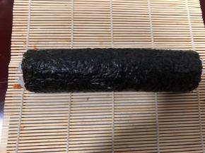 按照一定方法把寿司卷起来，卷紧一些。