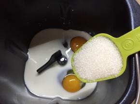 面包桶先倒入牛奶，打入鸡蛋，再放入糖，糖的对角放盐