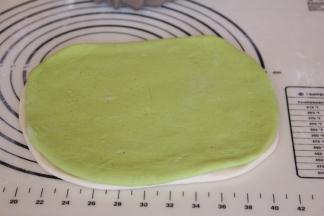 白色面团上方刷一层薄薄的水，将绿色面团盖住，轻轻用手按压