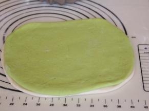 白色面团上方刷一层薄薄的水，将绿色面团盖住，轻轻用手按压