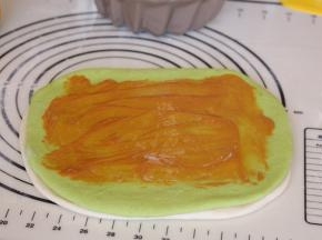 在绿色面团上方涂抹花生酱，四周不要涂抹