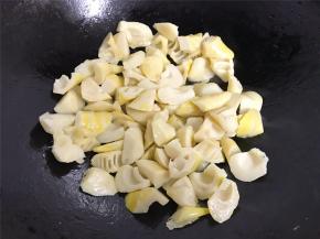 锅中倒入适量油，放入沥干水份的笋块，翻炒至微黄色。