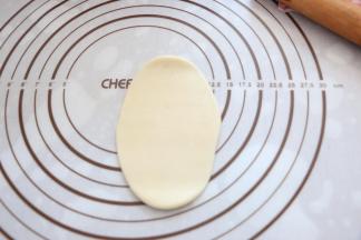 取松弛好的面团，压扁，擀成鸭舌状。