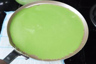 在炉边准备一条湿毛巾，轻轻将锅放上冷却一下，倒入抹茶面糊，晃至均匀布满整个不沾锅