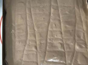 翻拌均匀，记得从底部充分翻拌，以免蛋黄糊残留在盆底。把蛋糕糊倒入铺了油纸的烤盘中，刮板抹平表面，并用牙签划几下，划出气泡。