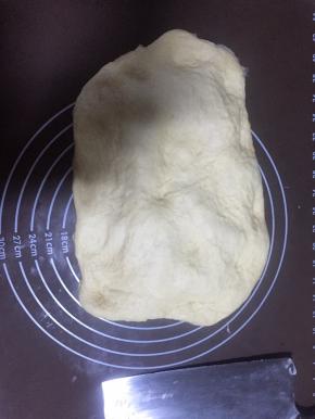 把发酵好的面团拿出来放在揉面垫上按压排出空气