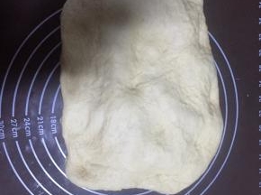 把发酵好的面团拿出来放在揉面垫上按压排出空气