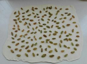 将面团擀成薄的长方形，均匀撒上葡萄干