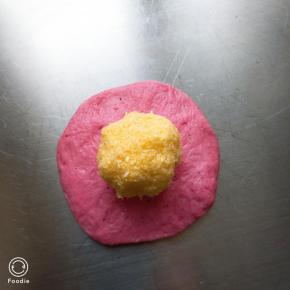 松弛好的面团取一个按扁包入椰蓉馅，全部包好盖保鲜膜再松弛15分钟