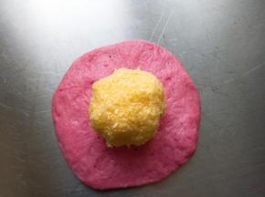 松弛好的面团取一个按扁包入椰蓉馅，全部包好盖保鲜膜再松弛15分钟