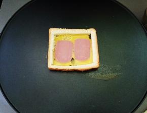 倒入一层的蛋液，放上两片的火腿片(想要下面的鸡蛋液厚些的话，先下入蛋液煎至凝固，再加入火腿片)