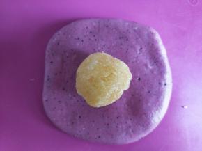 取一个面团擀开，放入一个椰蓉馅，包起来滚圆。