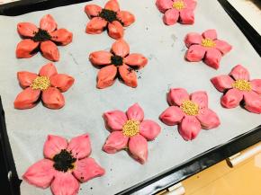 捏好后，放入烤盘中，用小刀在每个花瓣上划几下，花心涂蛋黄液，撒上黑芝麻，白芝麻或黑芝麻粉都可以（这是两个颜色）