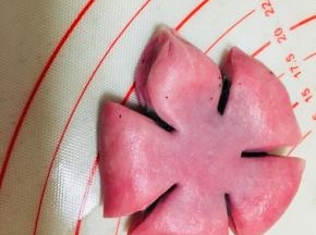 将包裹好的面团按扁，平均分成5份，用剪刀剪开，中间不要剪断，捏紧扇形顶端部分，捏出花瓣。
